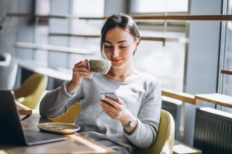 Woman sipping coffee while checking her phone