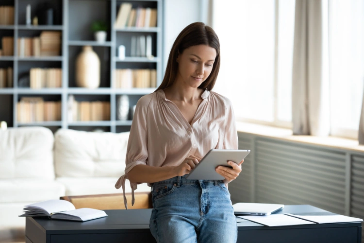 Young woman reviewing loan information on a tablet in a bright home office