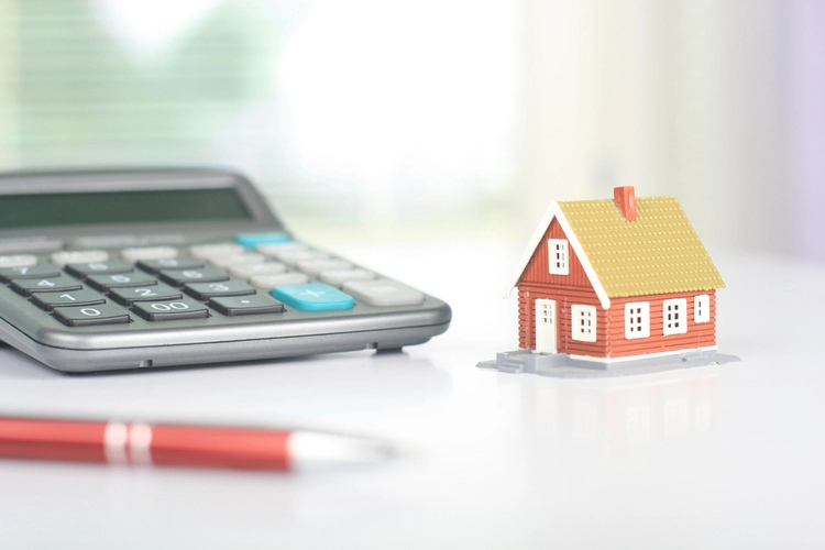 Model house beside a calculator on a desk