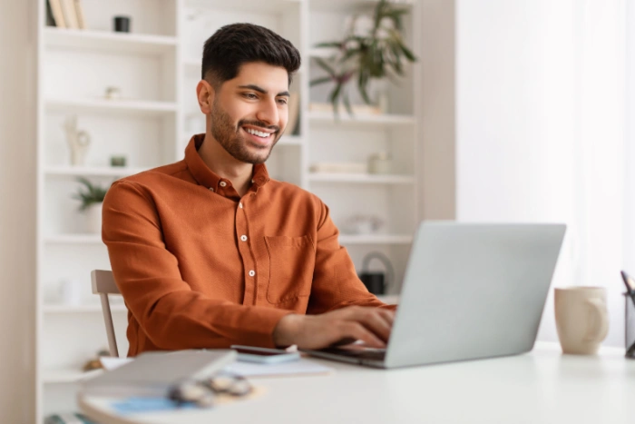 Man smiling while using a laptop at home