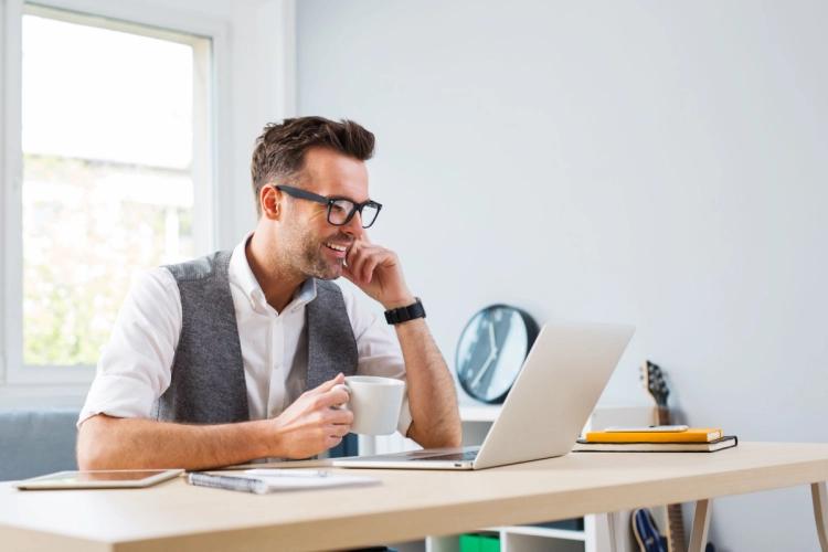 Man smiling while using a laptop at home