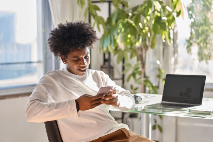 Young man reviewing loan alternatives on his phone at home