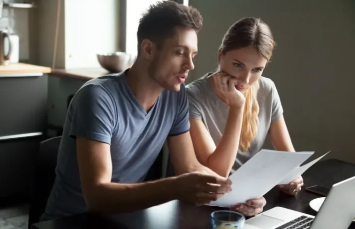 Couple reviewing loan papers at a laptop