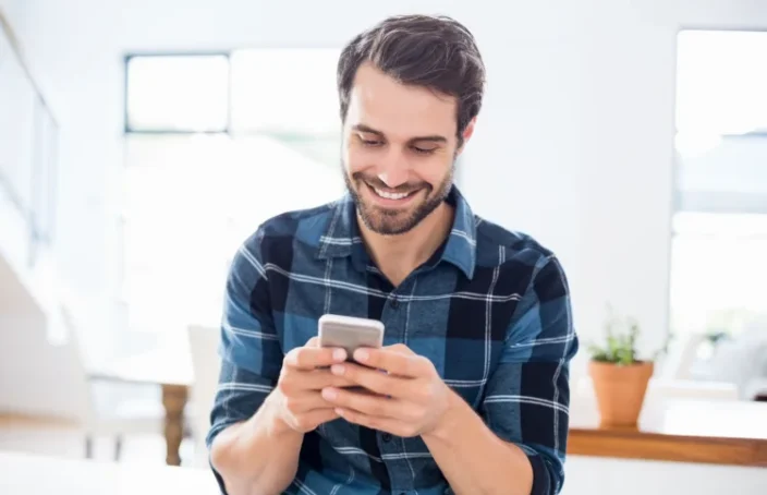Smiling man checking phone messages