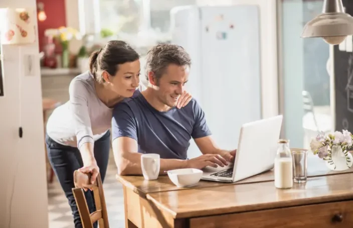 Couple using a laptop at a kitchen table