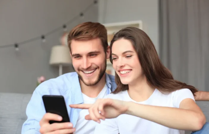 Smiling couple reviewing loan options on a phone