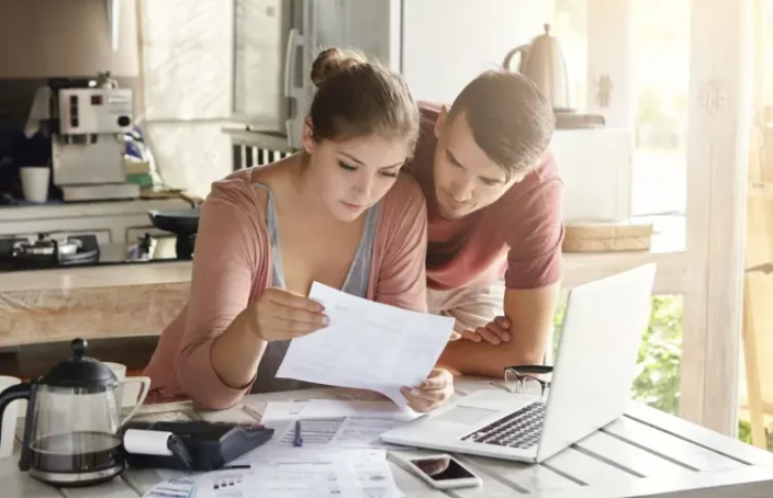 Couple reviewing bills and loan paperwork at a kitchen table