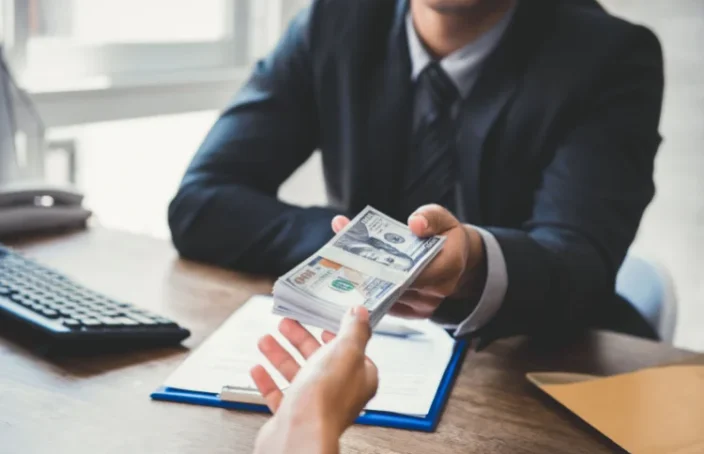 Person handing cash to another across a desk